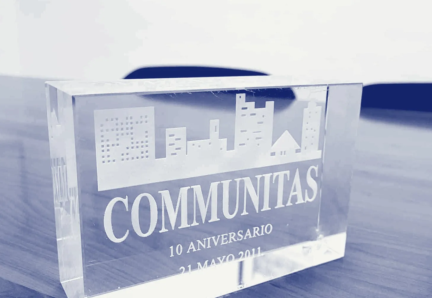 Placa de cristal grabada con el logotipo de Communitas y el texto «10 aniversario, 21 mayo 2011», sobre la mesa de juntas.